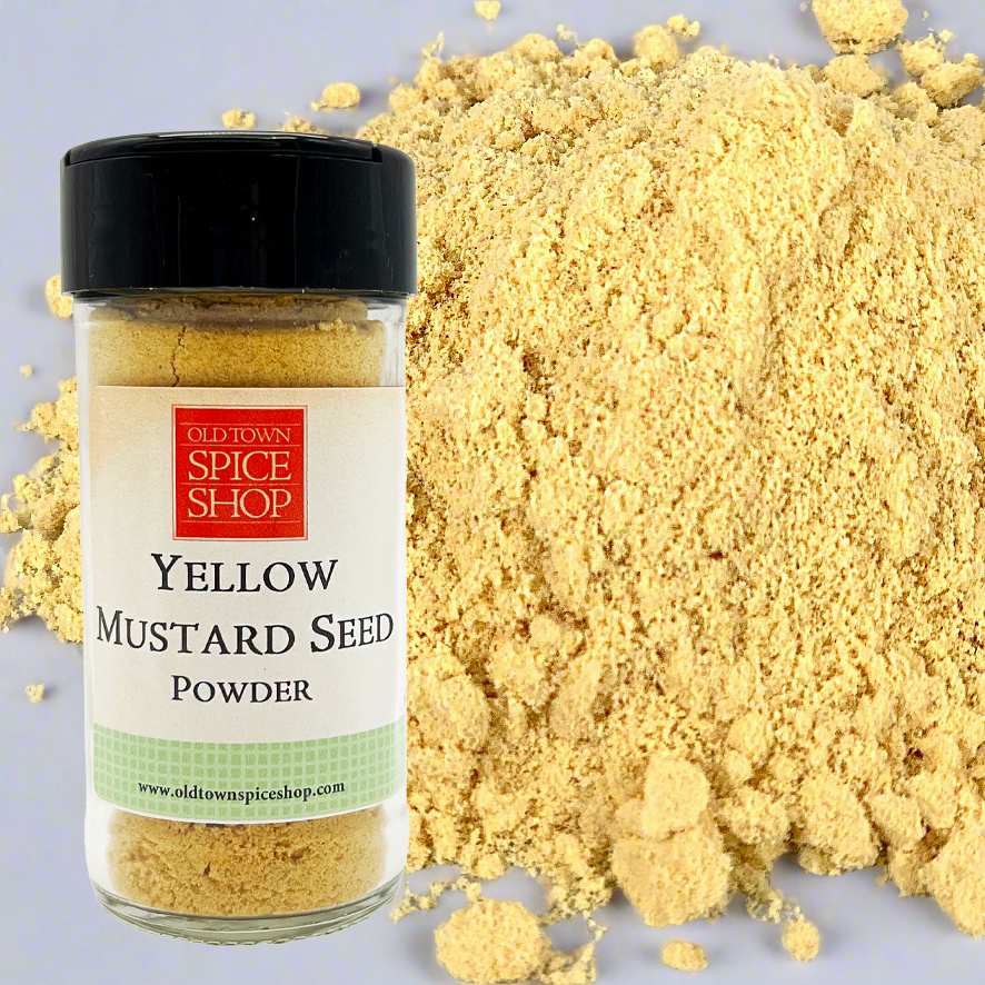 Yellow mustard seed powder with a jar labeled 'Old Town Spice Shop' on a gray background