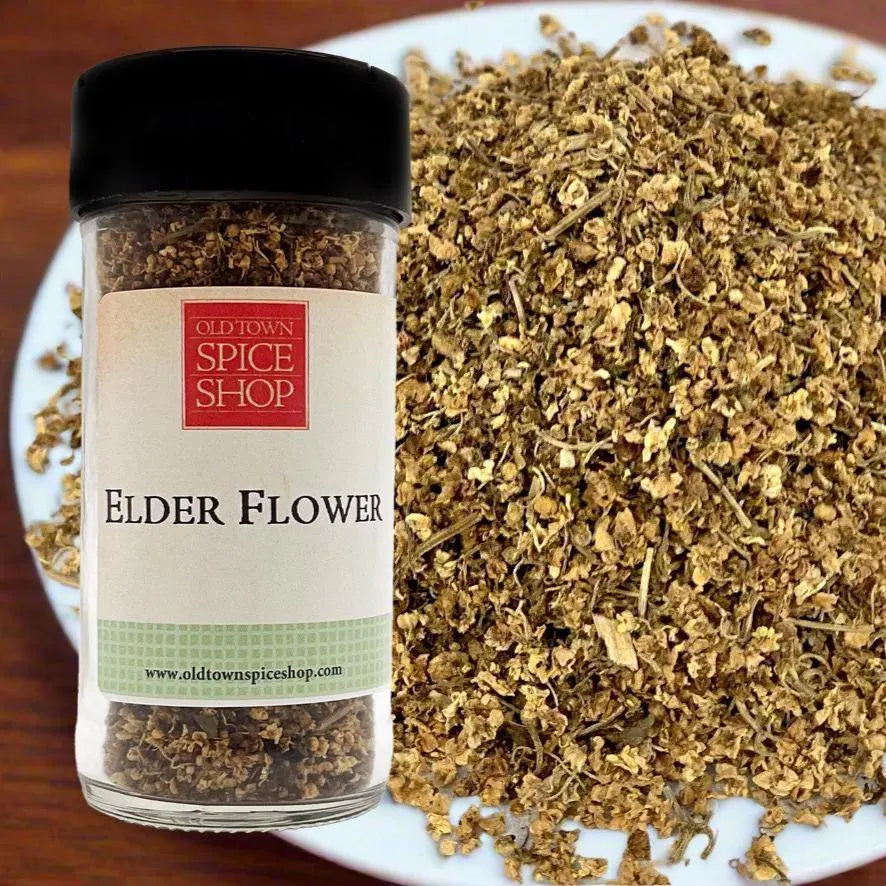 Jar of dried elder flower from Old Town Spice Shop on a white plate with more dried elder flowers.