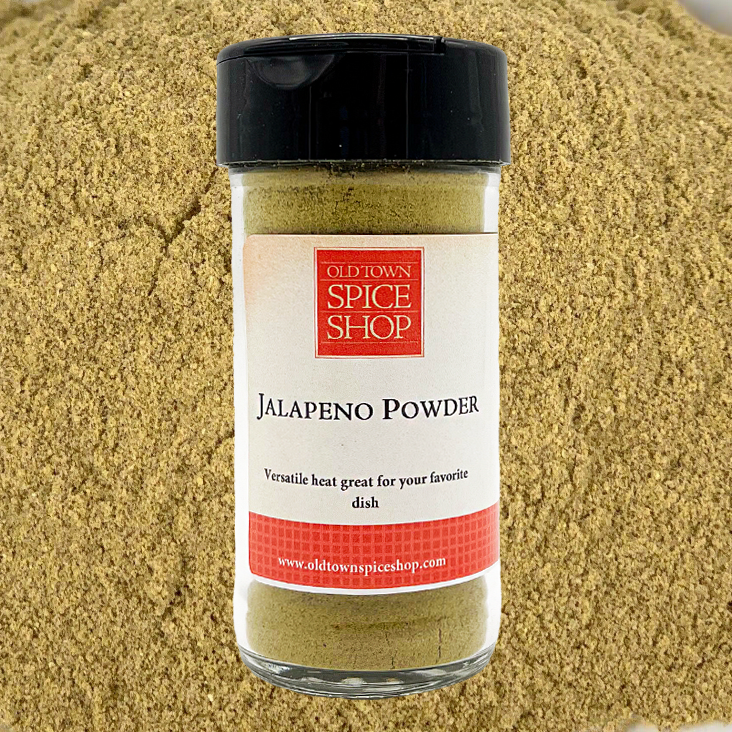 Jalapeno powder jar from Old Town Spice Shop on a bed of ground pepper.
