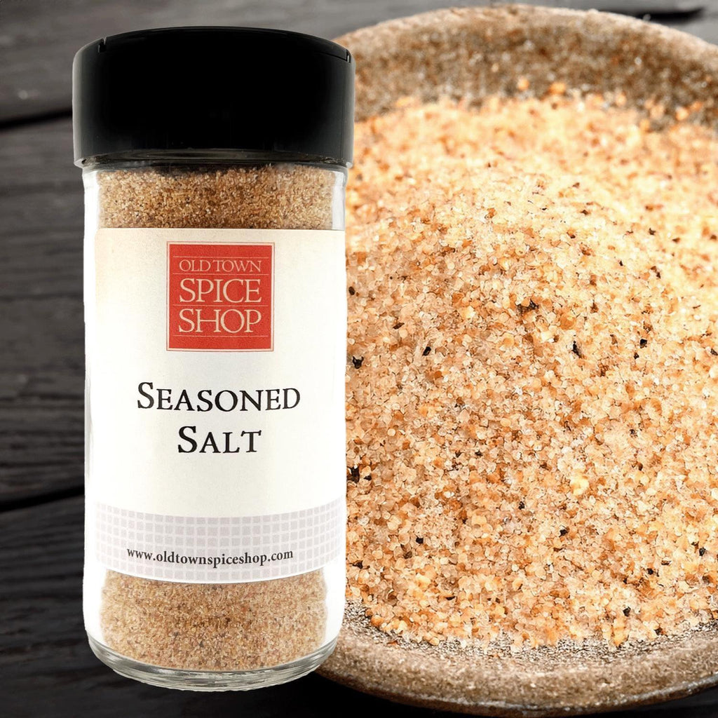 Bottle of Old Town Spice Shop seasoned salt next to a bowl of the product on a wooden surface.