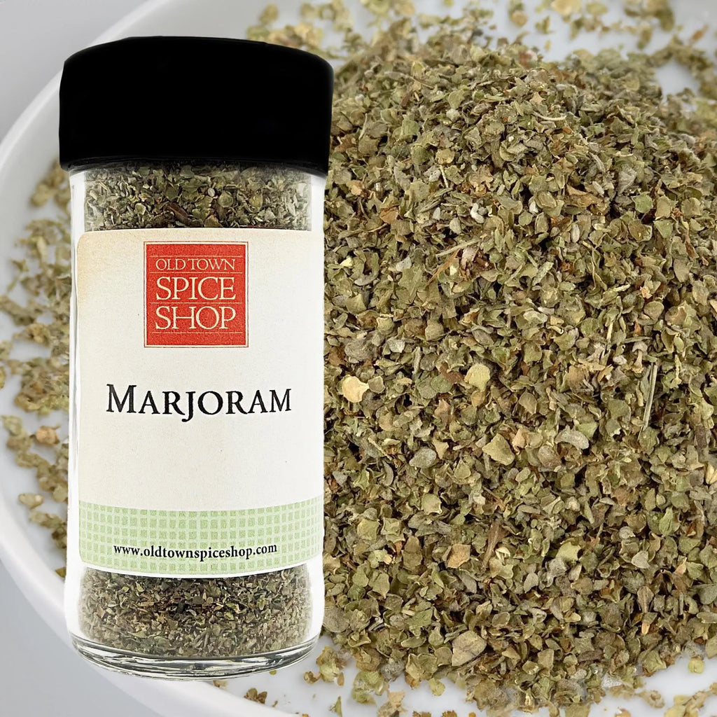 Jar of Old Town Spice Shop marjoram spice with marjoram leaves on a white plate.