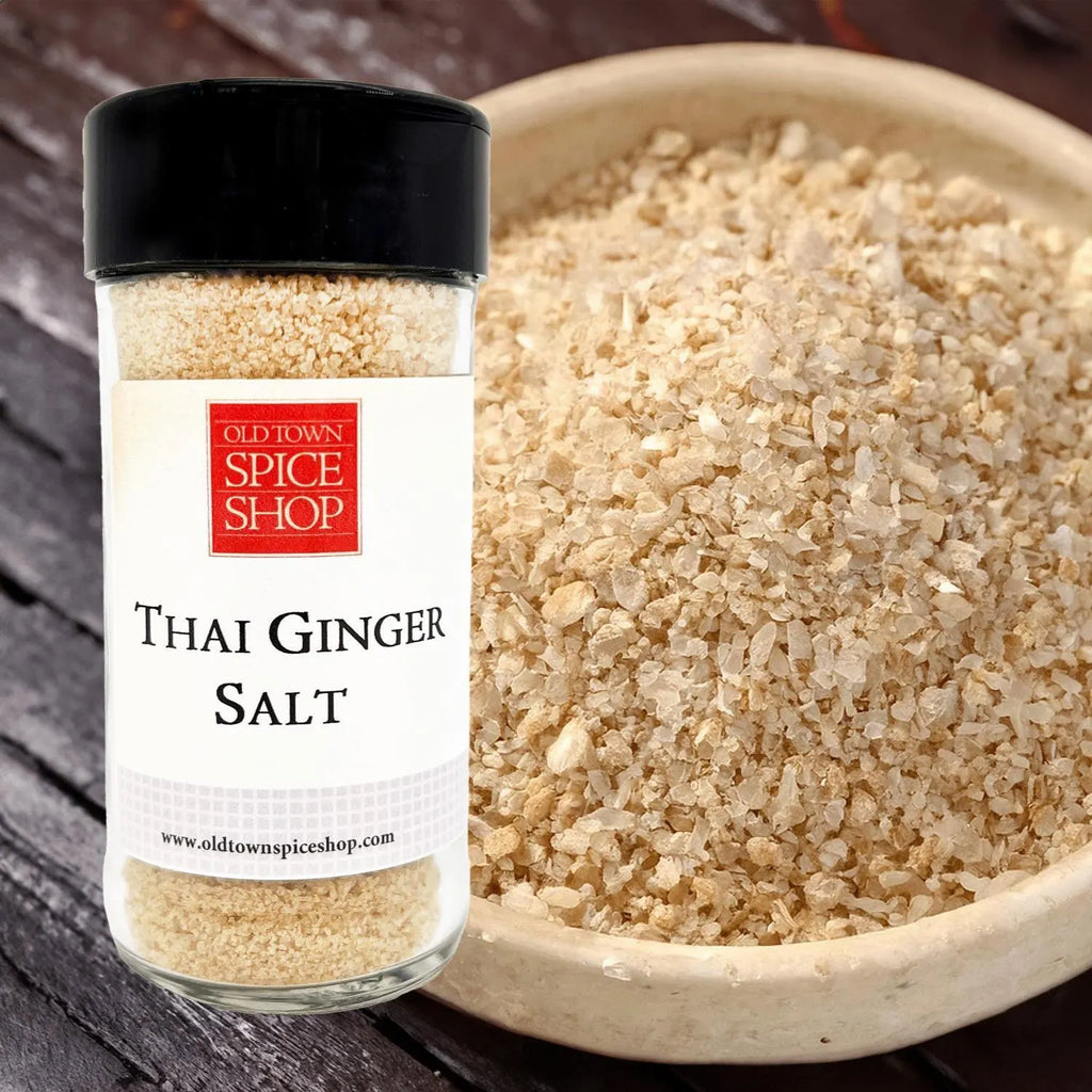 Jar of Old Town Spice Shop Thai Ginger Salt next to a bowl of the salt on a wooden surface.