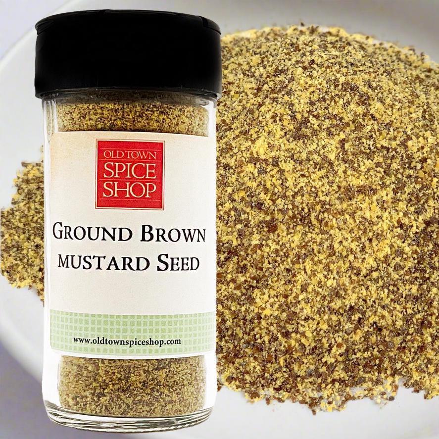 Jar of Old Town Spice Shop ground brown mustard seed with mustard seeds on a white background
