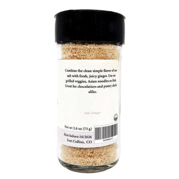 Glass container of salt and ginger with a black lid on a white background