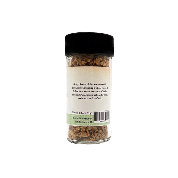 Glass jar with black lid containing ginger, on a white background