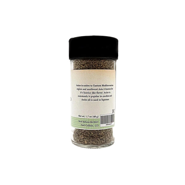 Jar of dried anise seeds with a black lid on a white background