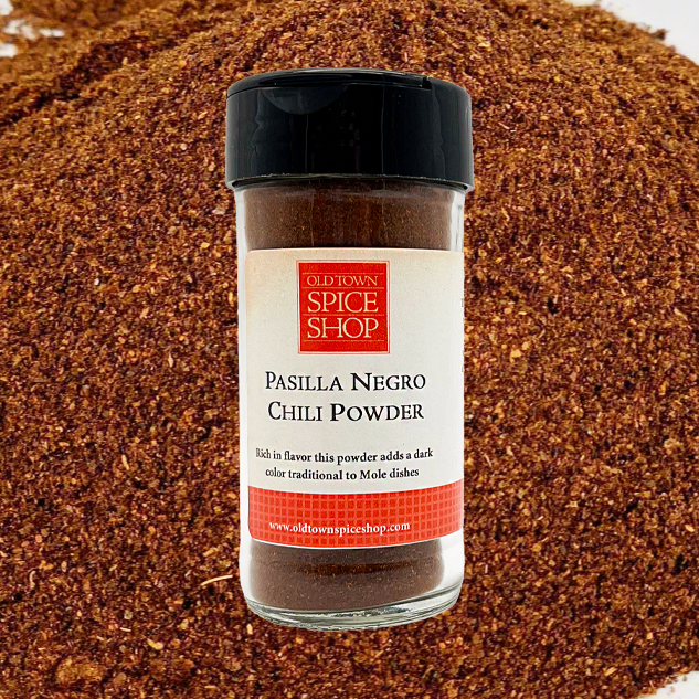 Bottle of Pasilla Negro Chili Powder from Old Town Spice Shop on a background of chili powder.