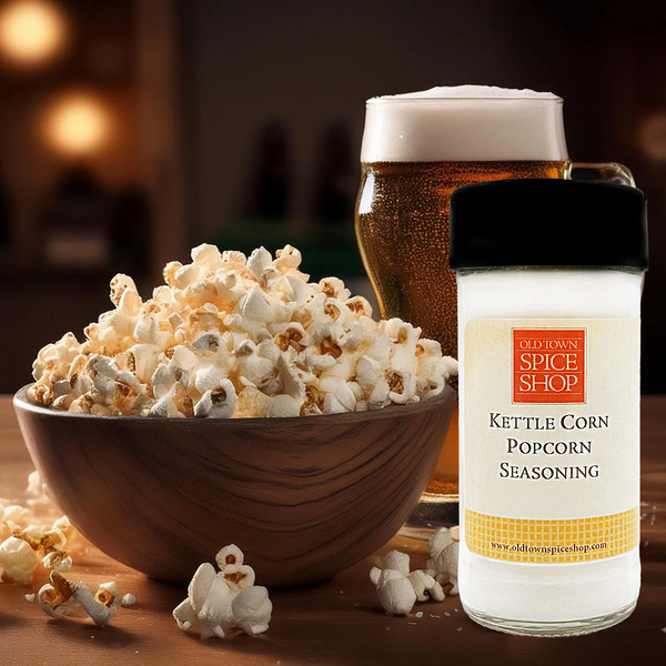 Bowl of popcorn, glass of beer, and bottle of Old Town Spice Shop Kettle Corn Popcorn Seasoning on a wooden surface.