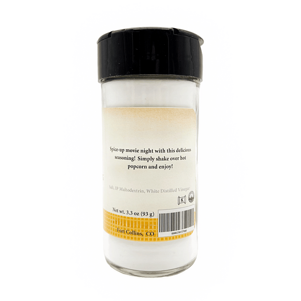 Glass seasoning shaker with black lid on a white background
