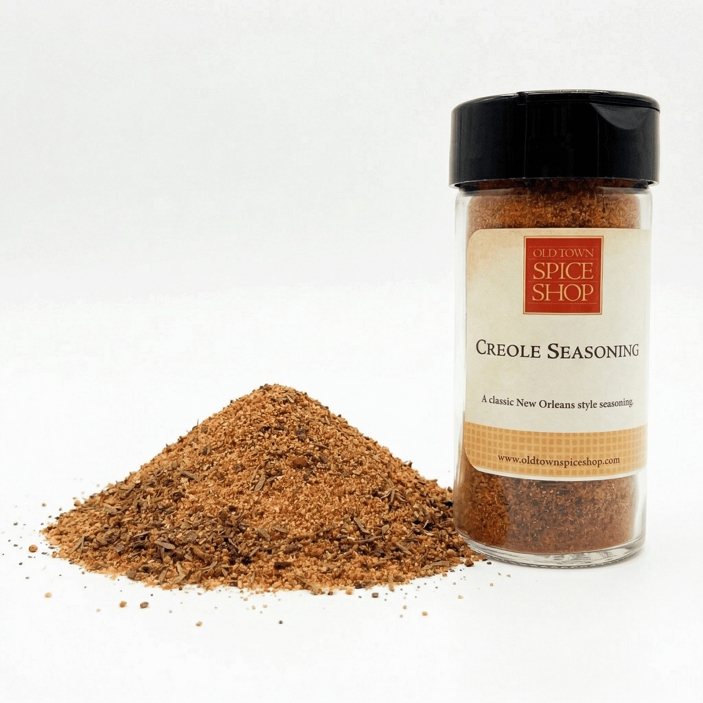 Creole seasoning jar with a pile of seasoning on a white background