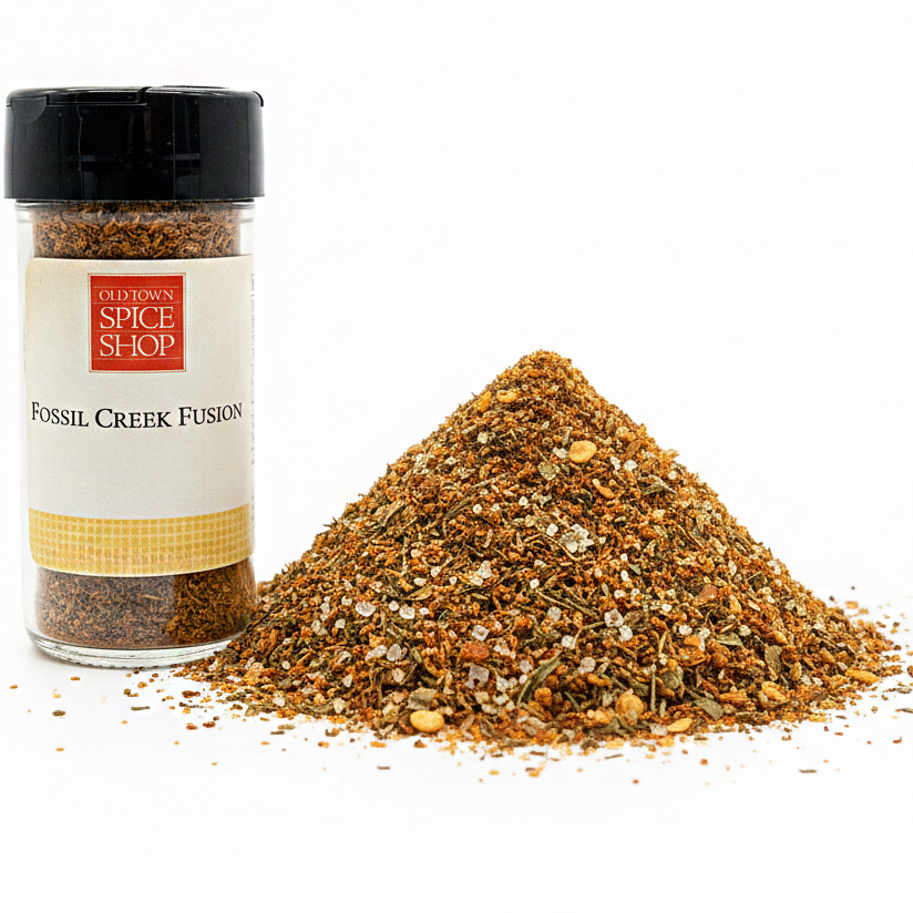 Spice jar labeled 'Fossil Creek Fusion' from Old Town Spice Shop with spilled spice mix on a white background