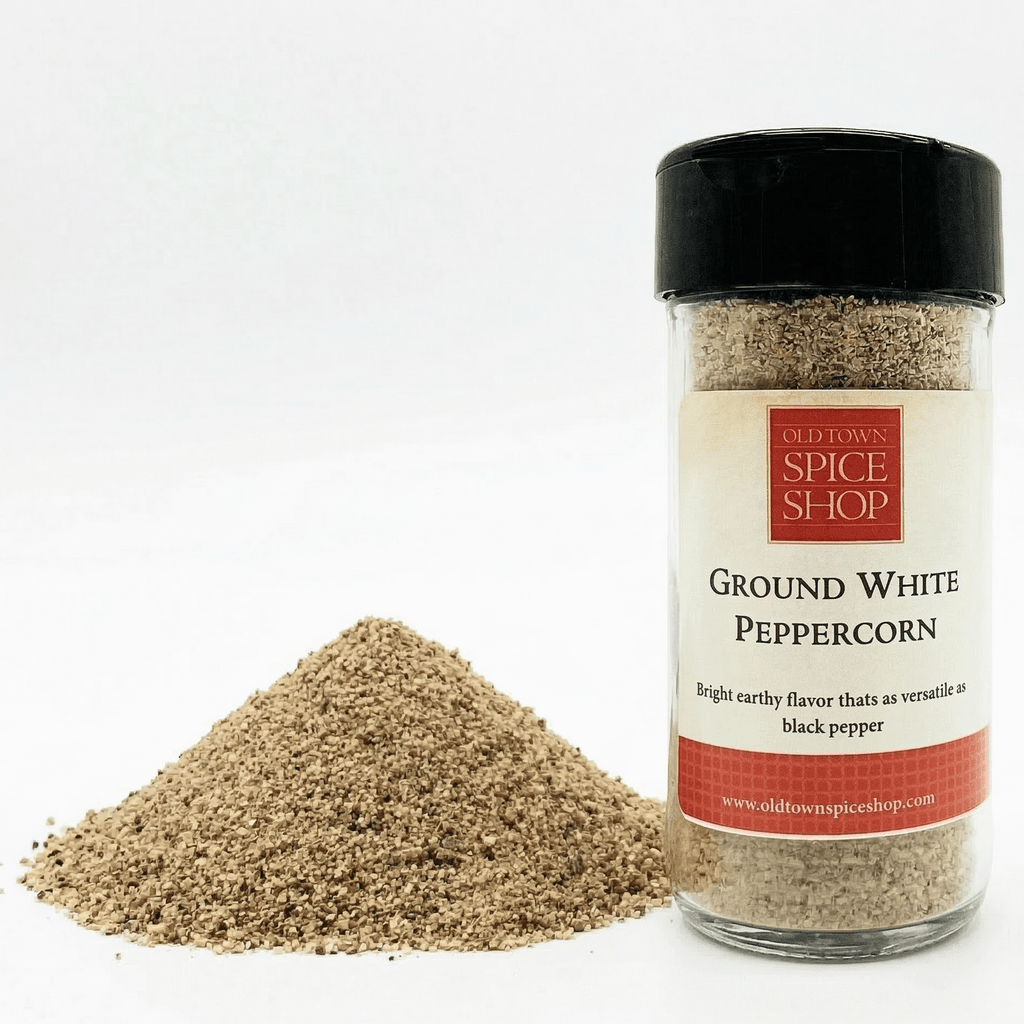 Bottle of ground white peppercorn with a pile of peppercorns on a white background