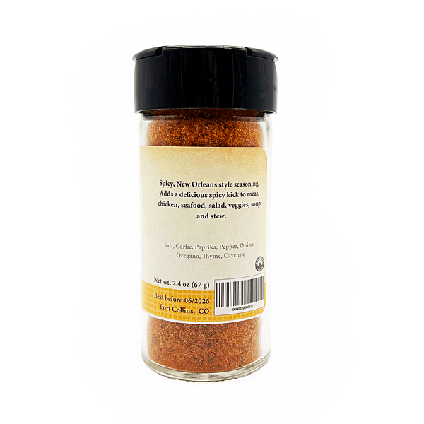 Spicy New Orleans style seasoning in a glass jar with a black lid on a white background