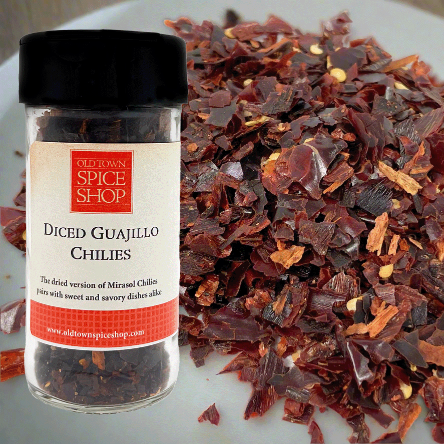 Jar of diced guajillo chilies from Old Town Spice Shop on a white plate with chilies.