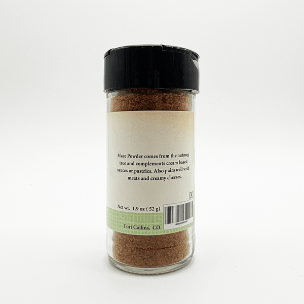 A clear plastic spice jar filled with brown powder, featuring a black flip-top lid and a cream label with product details and a light green band near the bottom.