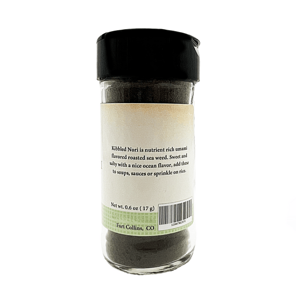 Glass container of kibbled nori with a black lid on a white background