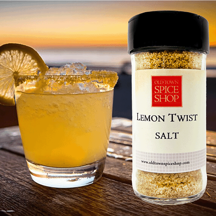 Glass of lemonade with a lemon twist next to a container of Old Town Spice Shop Lemon Twist Salt.