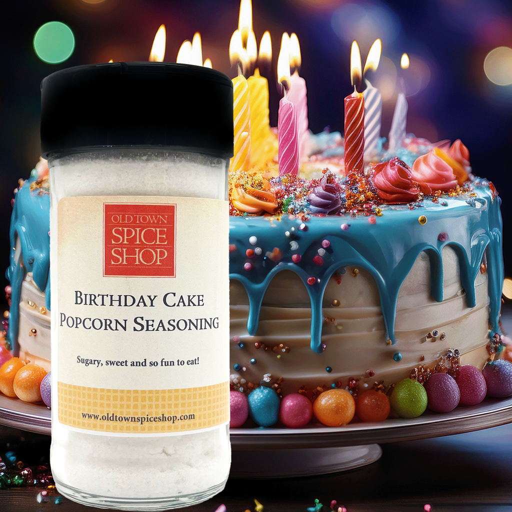 Spice Shop Birthday Cake Popcorn Seasoning bottle in front of a birthday cake with lit candles.