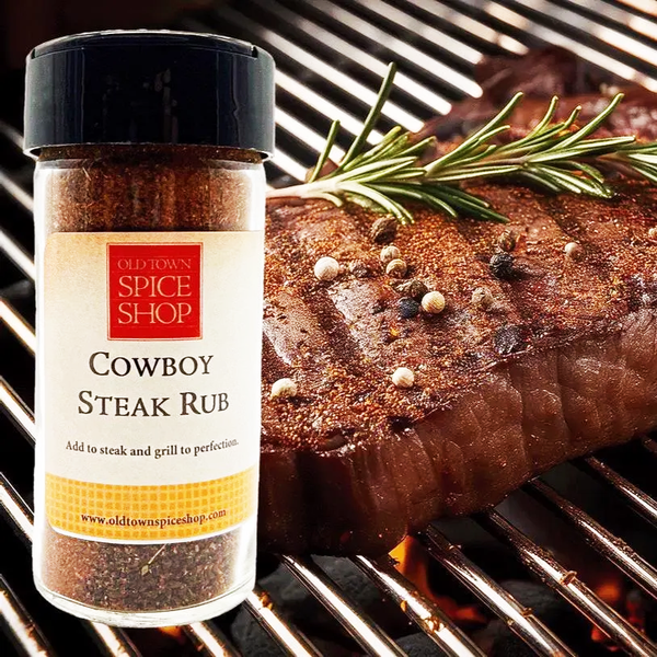 Old Town Spice Shop Cowboy Steak Rub bottle with a grilled steak on a grill.