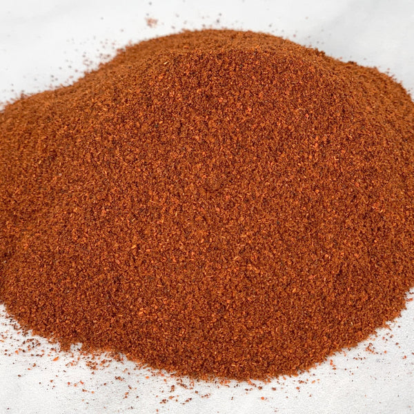 A pile of brown chili pepper powder on a white surface.